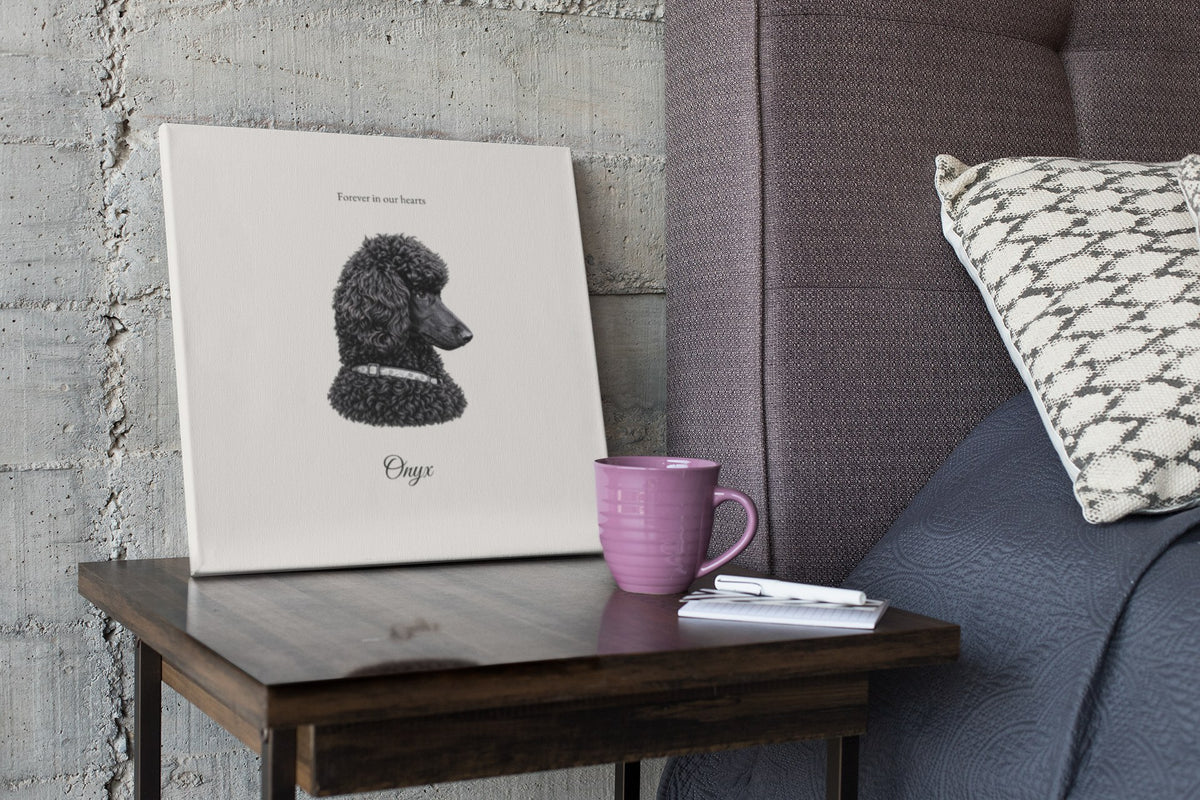 B&W charcoal memorial canvas of a black poodle with a tribute line, on a side table