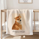 A personalized dog portrait blanket is draped over a wooden crib.