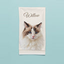 A folded blanket with Willow’s cat portrait and name on an aqua backdrop.