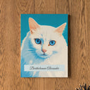 A bright cat portrait canvas with a name hangs on a warm wood wall.