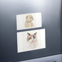 A dog portrait magnet and a cat portrait magnet are arranged on a refrigerator door.