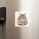 A tabby cat portrait magnet sits beside a refrigerator water dispenser.