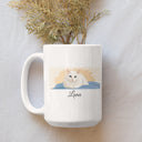 A white Luna cat portrait mug rests on pale fabric beneath dried flowers.