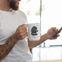 A man holds a personalized poodle portrait mug while checking his phone.
