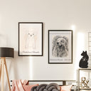 Two framed dog portraits hang above a sofa, one with a memorial inscription.