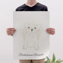 A person holds a personalized dog portrait poster against a light backdrop.