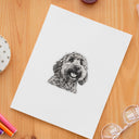 A charcoal dog portrait sticker decorates a white notebook on a wooden desk.