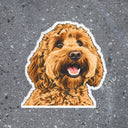 A colorful dog portrait sticker with a white border sits on speckled concrete.