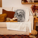 A memorial golden retriever blanket is draped over a sofa in an autumn room.