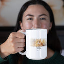 A woman holds a white Milo memorial mug toward the camera.
