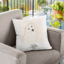 A Kiko memorial pillow rests on a gray armchair beside a bright balcony.
