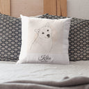 A Kiko memorial pillow rests between patterned pillows on a bed.