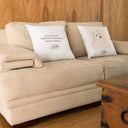 Two Kiko memorial pillows show the portrait and tribute sides on a cream sofa.