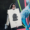 A woman holds a memorial dog portrait poster in front of a colorful mural.